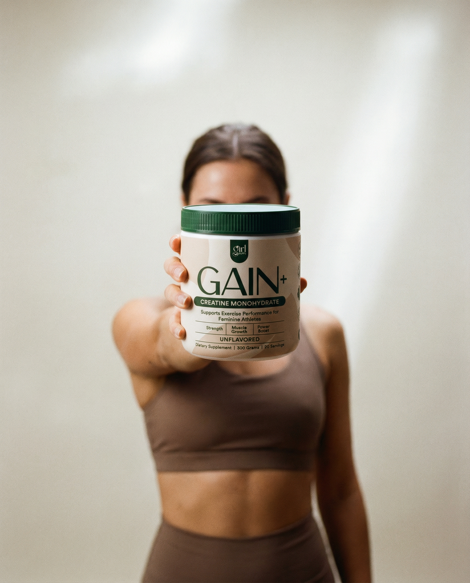 Person holding a container labeled 'Gain+' against a neutral background
